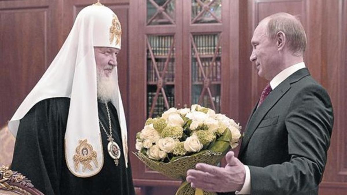 El presidente ruso, Vladimir Putin, entrega un ramo al patriarca de la Iglesia ortodoxa rusa, KIrill, ayer.