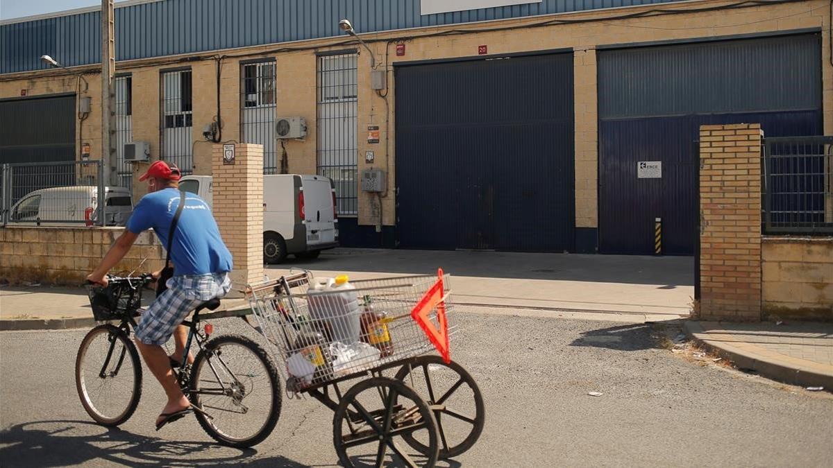 Un hombre pasa en bicicleta por delante de la empresa Magrudis en Sevilla, cerrada por su vinculación al brote de listeriosis, el 22 de agosto del 2019