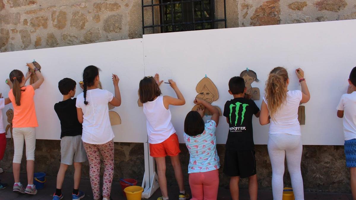 Varios niños dibujan sobre un mural en una actividad en Navalmoral.