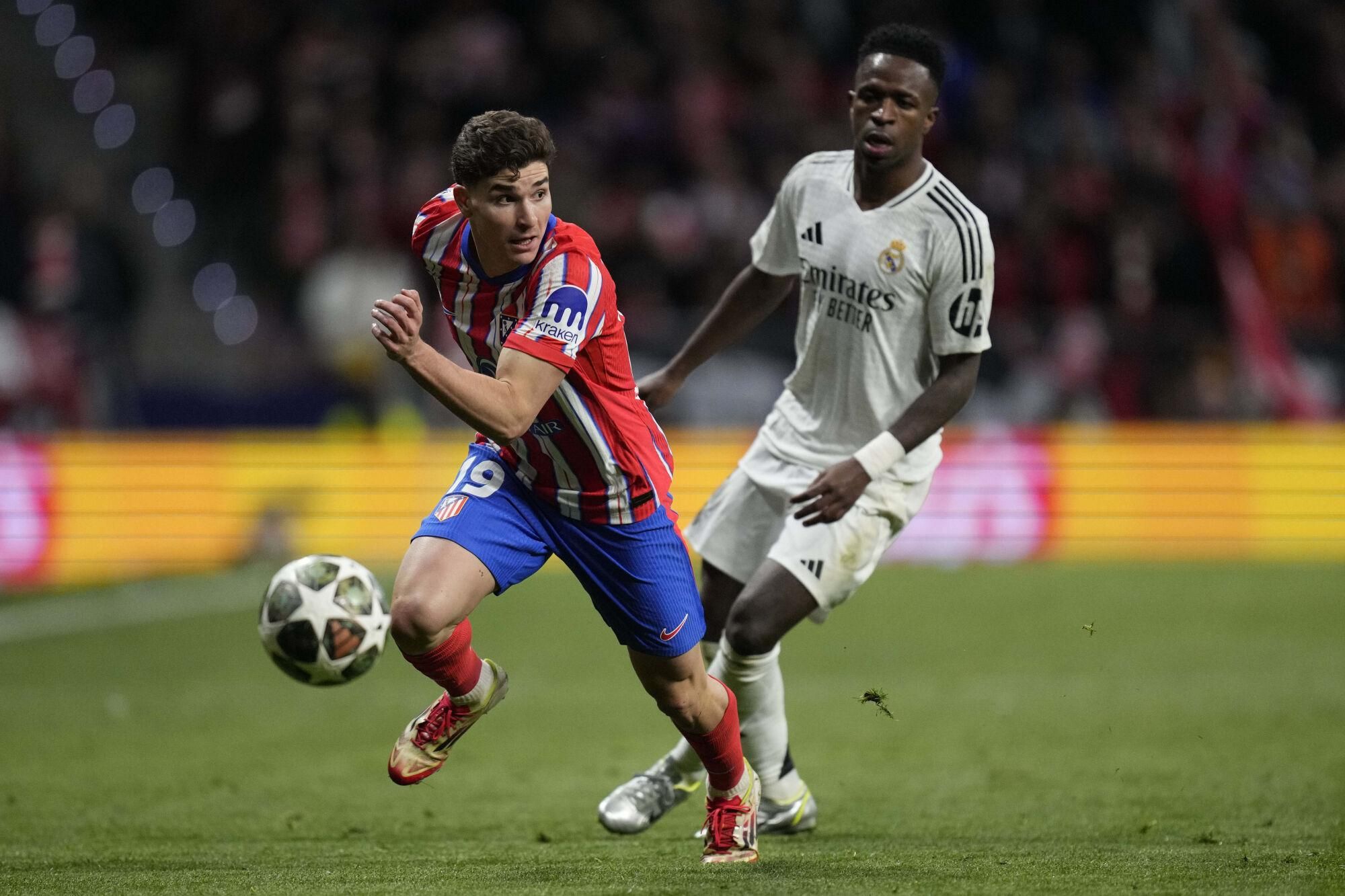 Atletico Madrid's Julian Alvarez in action in front of Real Madrid's Vinicius Junior during the Champions League round of 16, second leg, soccer match between Atletico Madrid and Real Madrid at the Metropolitano stadium in Madrid, Spain, Wednesday, March 12, 2025. (AP Photo/Bernat Armangue). EDITORIAL USE ONLY/ONLY ITALY AND SPAIN