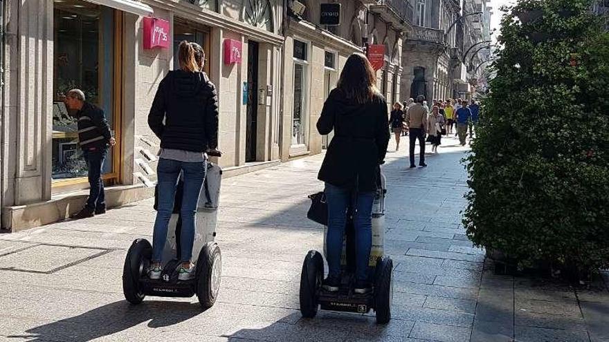 Dos turistas circulan en &quot;segways&quot; por la calle Príncipe. // A. Blanco