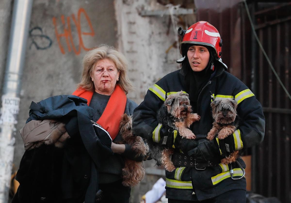 Un miembro de los servicios de rescate ucranianos ayuda a una mujer herida y a sus perros tras un bombardeo ruso en el centro de Kiev, el 10 de octubre de 2022.