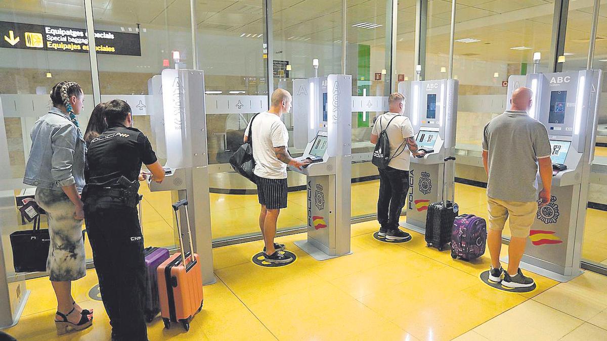 Passatgers a l’aeroport de Girona i passant pel sistema de control automàtic (arxiu).