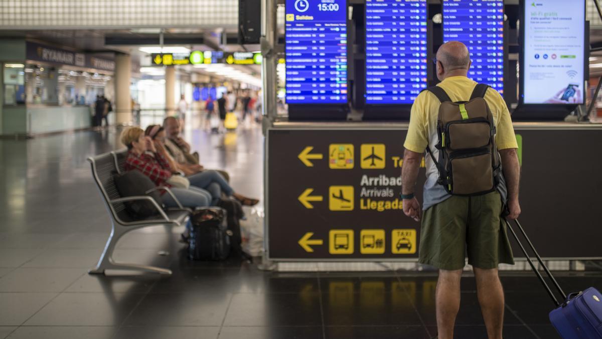 Un hombre mira un panel de llegadas y salidas en el Aeropuerto Josep Tarradellas Barcelona-El Prat.