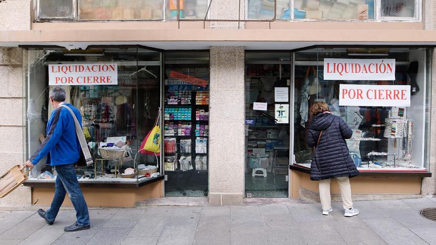 Dos comercios contiguos de Vigo, con carteles de liquidación por cierre. // Alba Villar