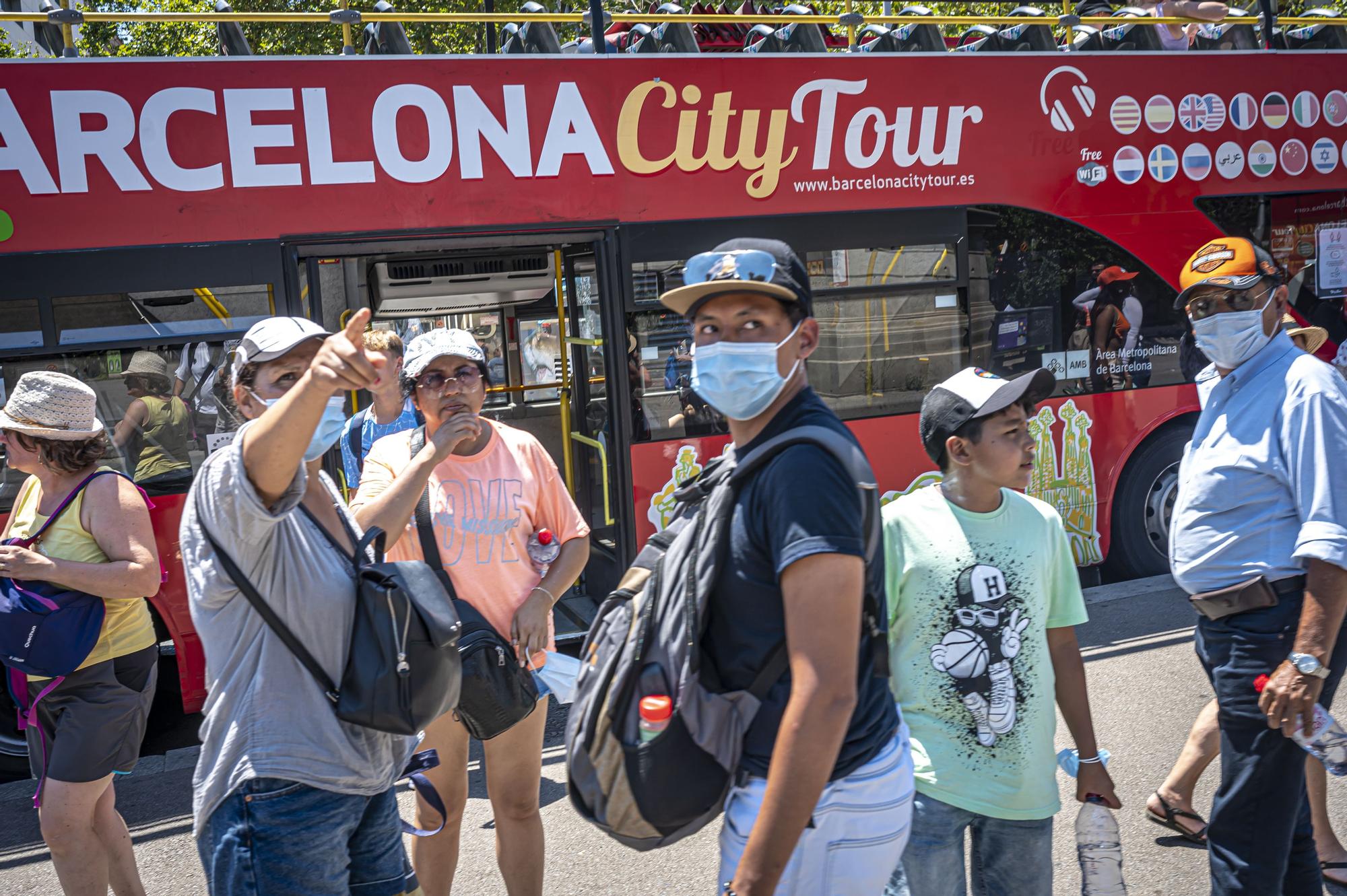 Turistas en el centro de Barcelona, junto a un bus que realiza rutas por la ciudad.