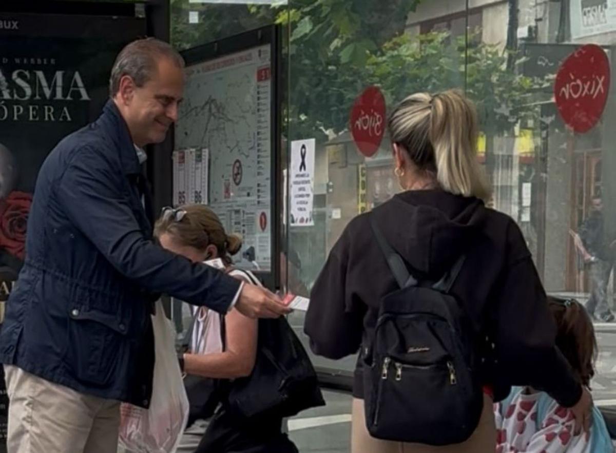 El concejal Tino Vaquero entrega un folleto a una viajera en una marquesina de Emtusa. | LNE