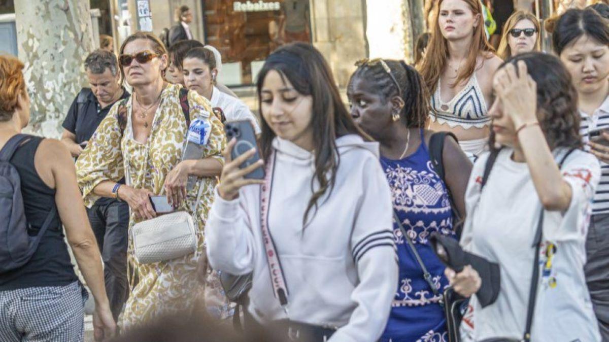 Una jove pendent del mòbil al creuar un pas de vianants.