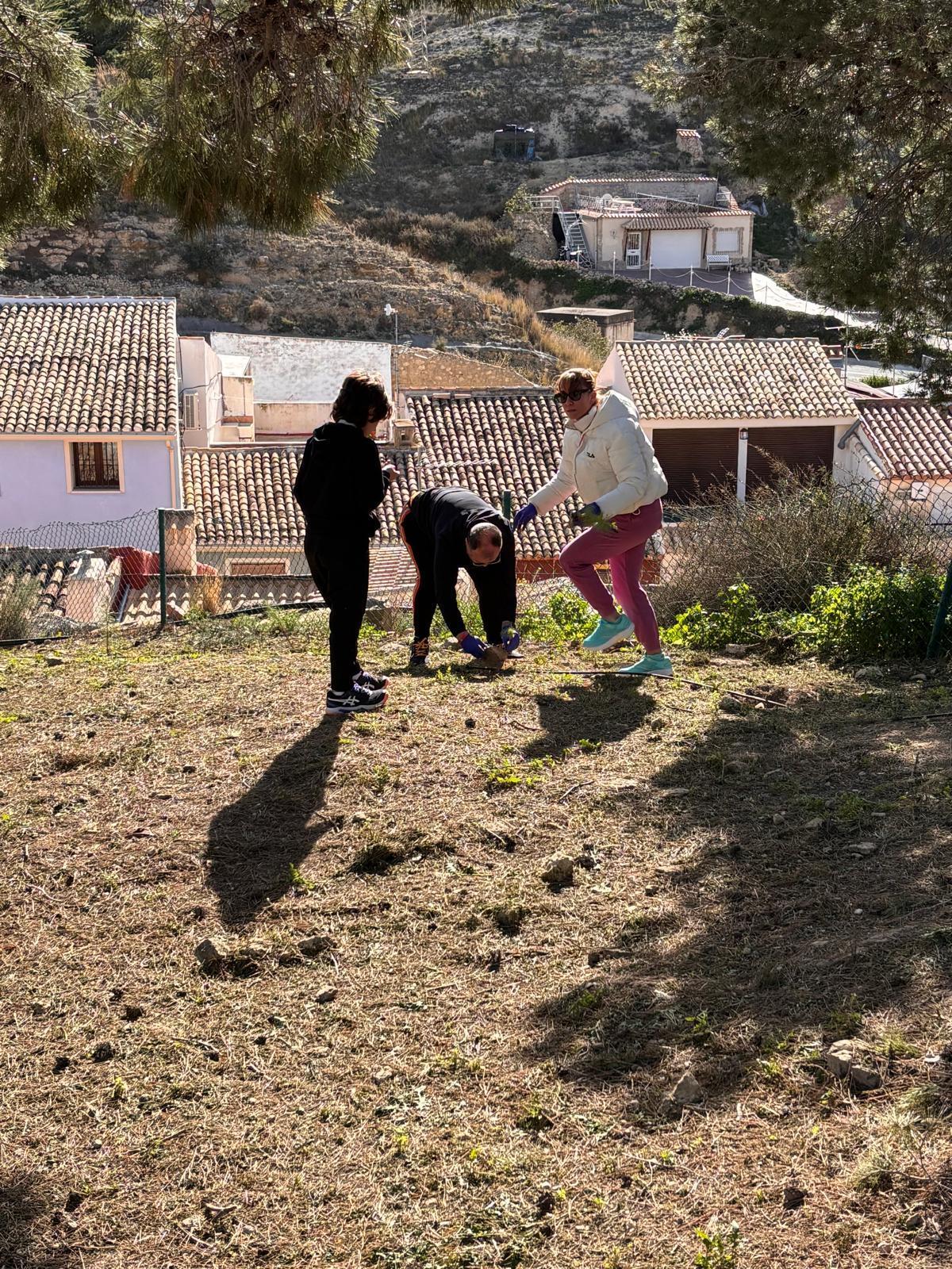 Tres participantes preparan la plantación de un árbol durante la actividad.