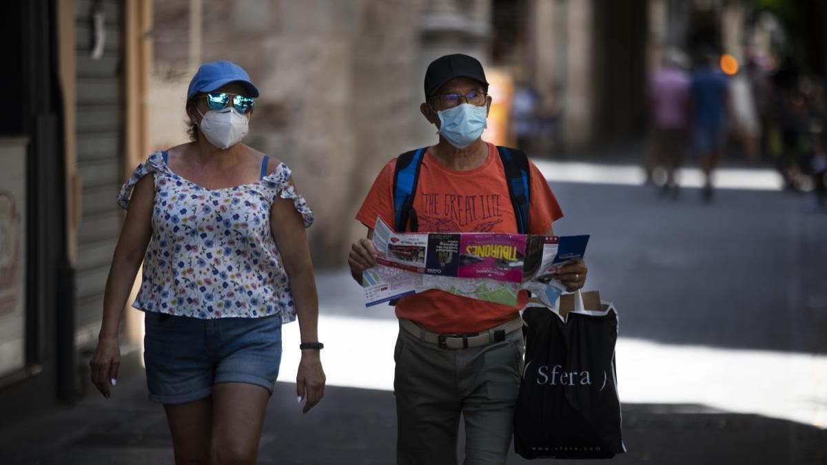 Dos turistas pasean con mascarilla por las calles del centro de València.