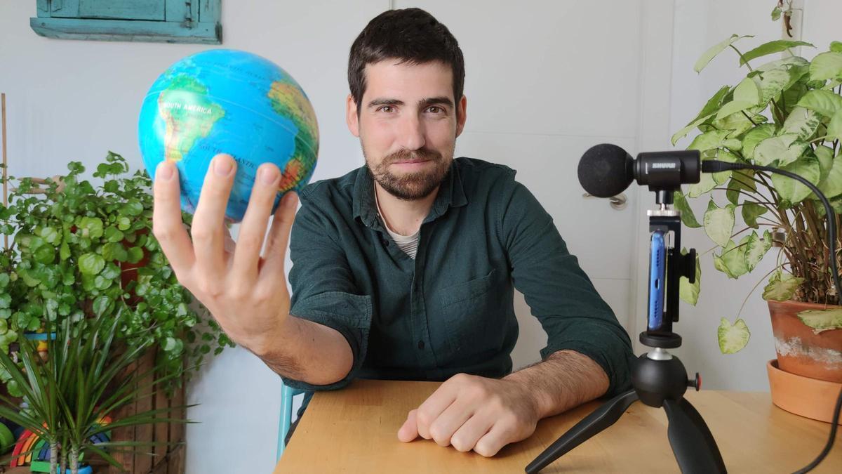 Javier Peña, divulgador climático, posa para la fotografía con un globo terráqueo