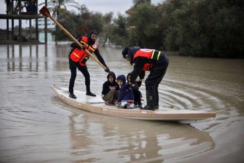 Members of the Palestinian civil defense ride a boat as they evacuate boys following heavy rains in Rafah