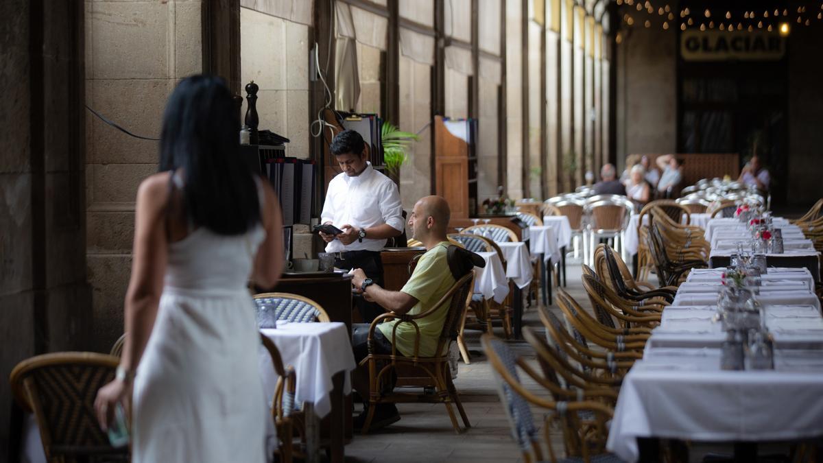Un camarero atiende a una mesa en la plaza Real de Barcelona.