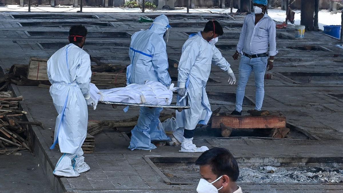 Personal sanitario traslada un cadáver de una persona fallecida por COVID-19 para su cremación, en Nueva Delhi (India). AFP