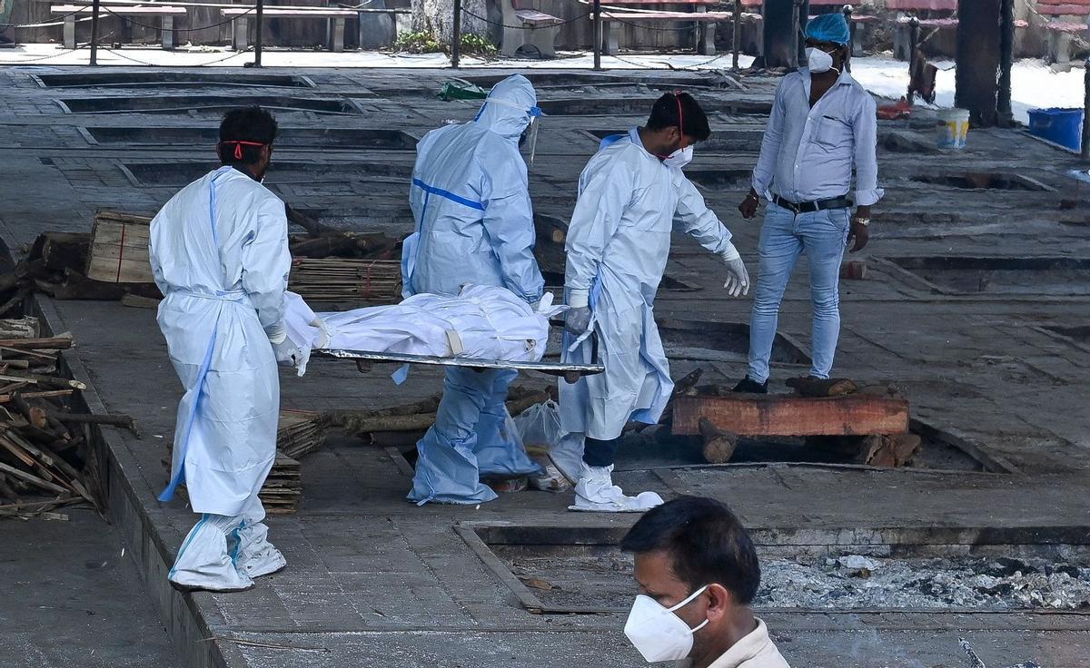 Ambulance staff carry a dead body for cremation, who died due to the Covid-19 coronavirus at a crematorium in New Delhi on May 21, 2021. (Photo by Prakash SINGH / AFP)