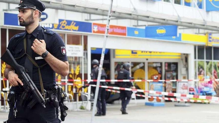 Un policía monta guardia frente al supermercado de Hamburgo donde tuvo lugar el ataque. // Efe