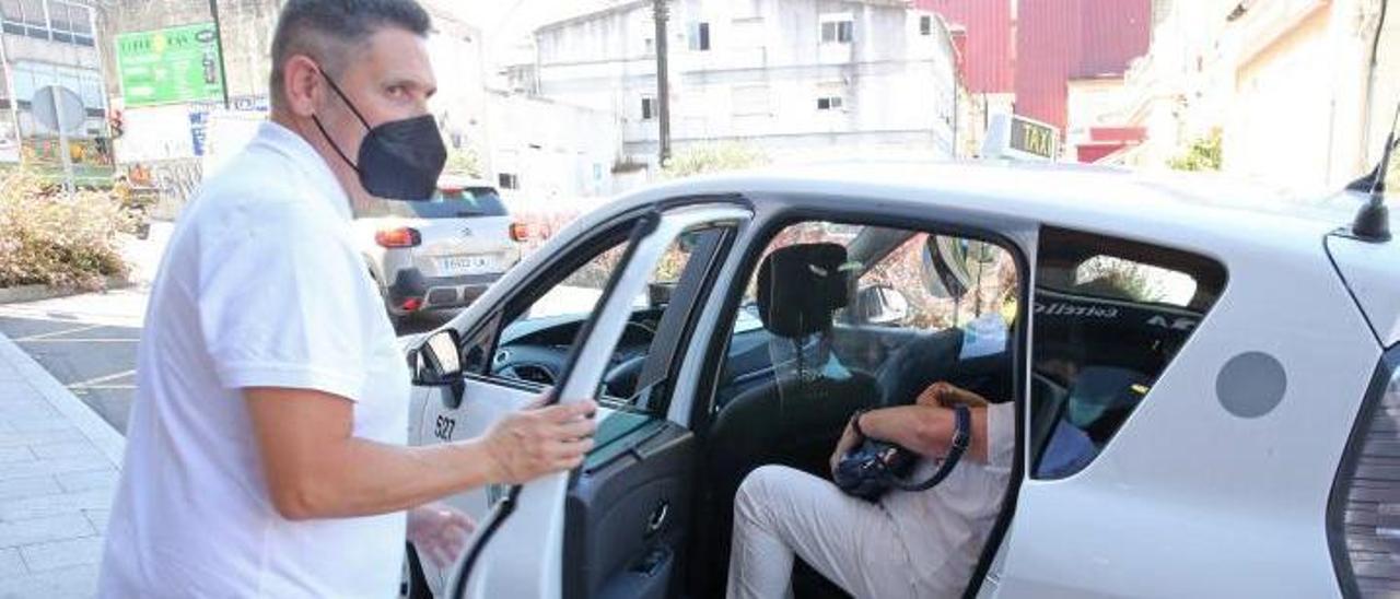Un taxista de Vigo ayuda a subir a una clienta al vehículo.