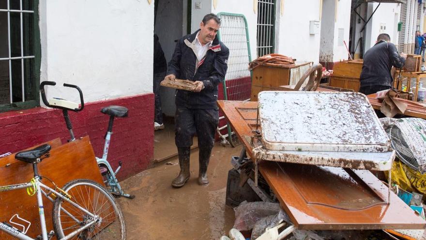 Un vecino de Campanillas saca muebles dañados de su vivienda.