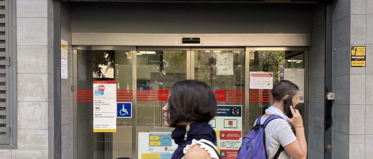 Dos personas pasan ante una oficina pública de empleo.