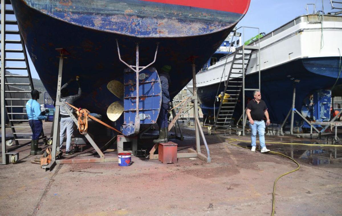 Los trabajadores, bajo uno de los barcos pesqueros. | GONZALO NÚÑEZ
