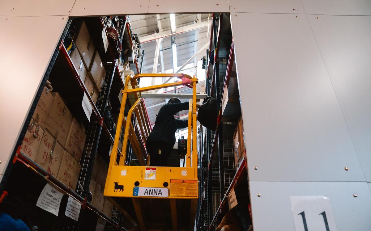 Una de las trabajadoras de la Oficina de Objetos Perdidos de Madrid coloca una maleta en la estantería del almacén.