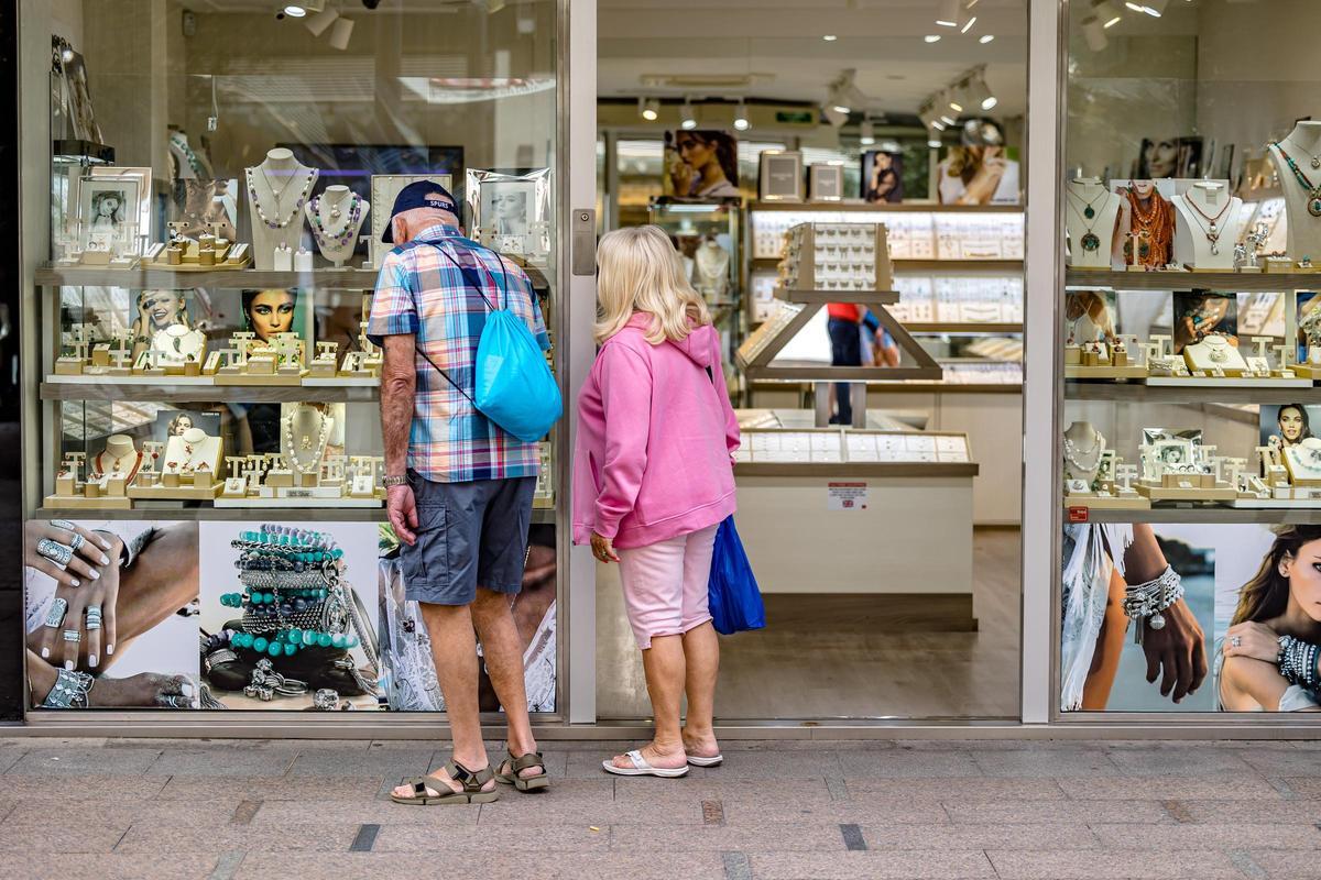 Una pareja de turistas mira el escaparate de una tienda en Benidorm.
