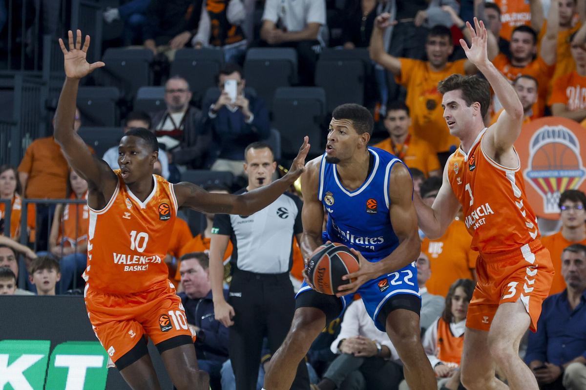 El pívot del Real Madrid Edy Tavares (c) disputa un balón con los jugadires del Valencia Omari Moore (i) y Nate Reuvers (d) durante el partido de la décima jornada de la fase regular de la EuroLiga entre el Valencia Basket y el Real Madrid, este viernes en Valencia. EFE/ Miguel Ángel Polo