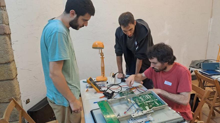 Tres voluntaris del taller reparant un televisor,  ahir | POL VILÀ