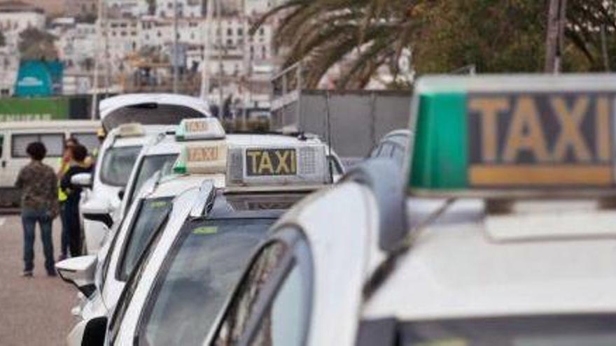 Una fila de taxis en la parada situada junto a las barcas de Formentera, con la vista de Dalt Vila al fondo.