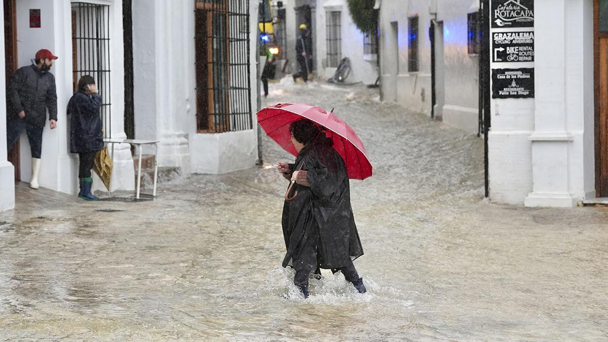Una vecina de Grazalema (Cádiz) camina por una calle inundada debido a las intensas lluvias