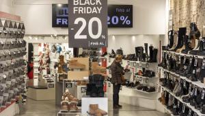 Una mujer observa zapatos en una tienda con una promoción del 20% de descuento la tarde antes del Black Friday oficial