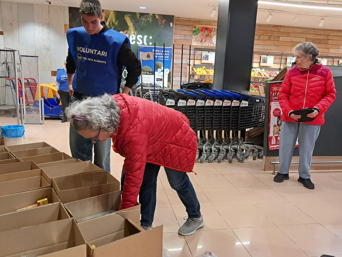 Pilar Romero col·loca la seva aportació al Gran Recapte en una capsa, amb ella, el voluntari Èric Martínez