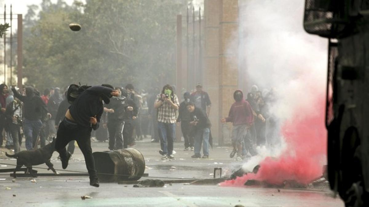 Un manifestante lanza una piedra a un vehículo de la policía, ayer en Santiago.