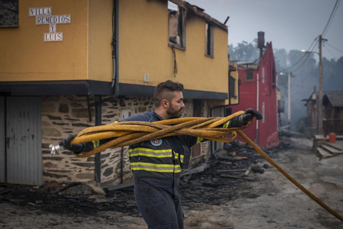 O BARCO DE VALDEORRAS (OURENSE), 18/07/2022.- Un bombero ante casas calcinadas en la localidad de Alixo (O Barco de Valdeorras), Galicia, que vuelve a afrontar una jornada decisiva para extinguir los incendios forestales que afectan a las provincias de Ourense y Lugo y que mantienen en riesgo varios núcleos de población. EFE/ Brais Lorenzo