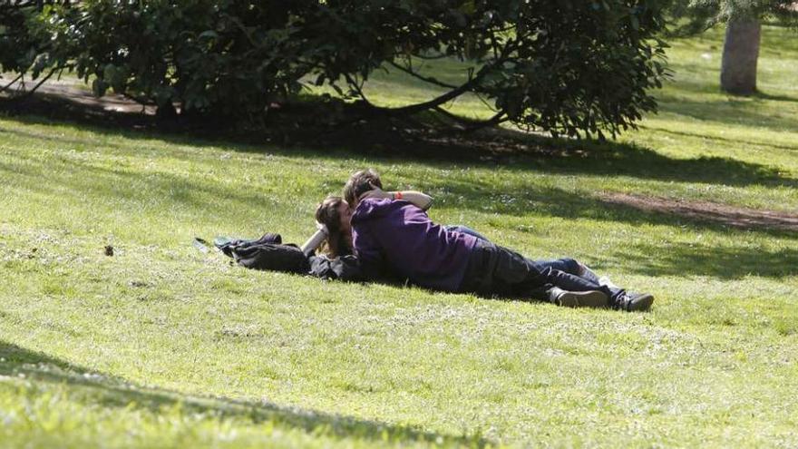 Una pareja de jóvenes se besa sobre la hierba.