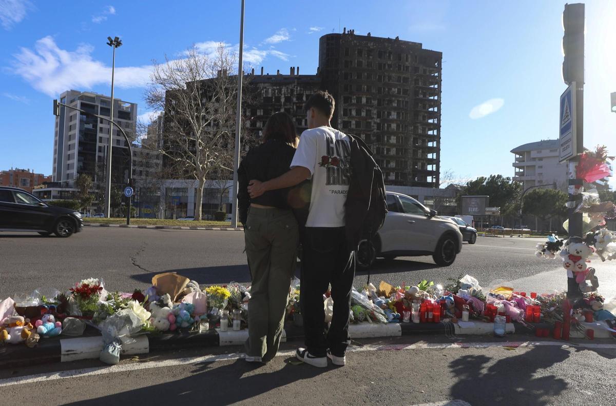 Dos jóvenes colocan flores en el altar para las personas fallecidas en el incendio de València.