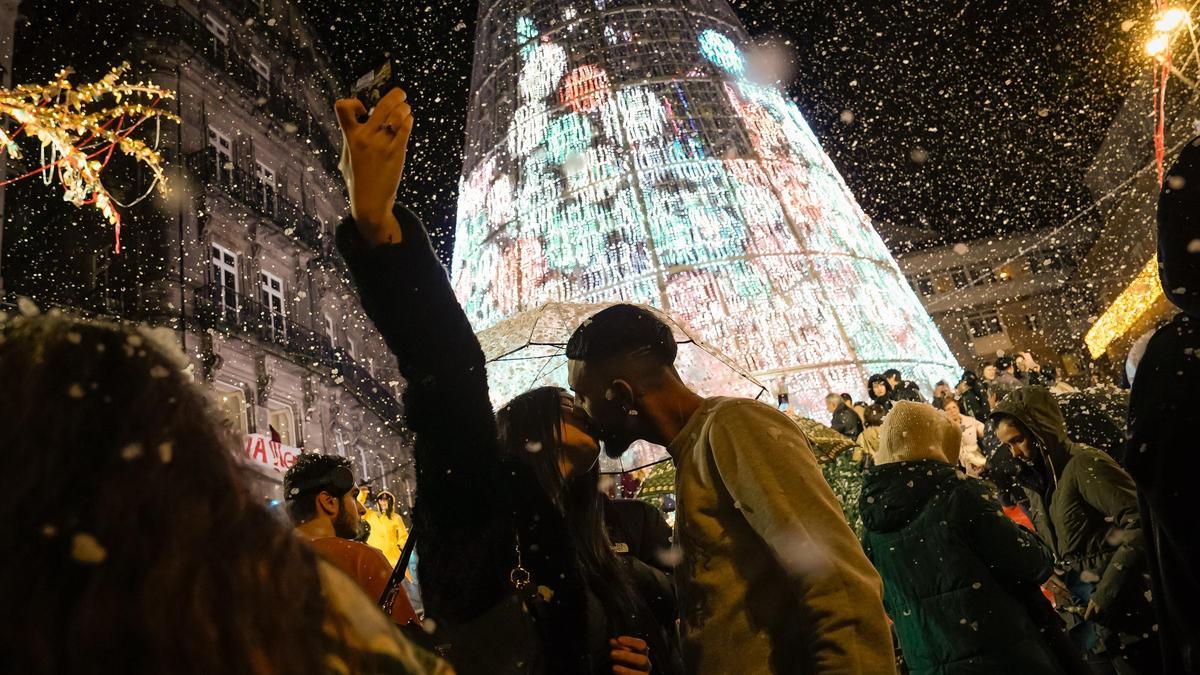 Una pareja se besa en mitad de un alumbrado navideño.