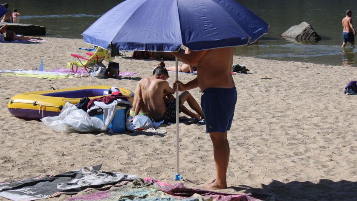 Un hombre coloca una sombrilla en una playa.
