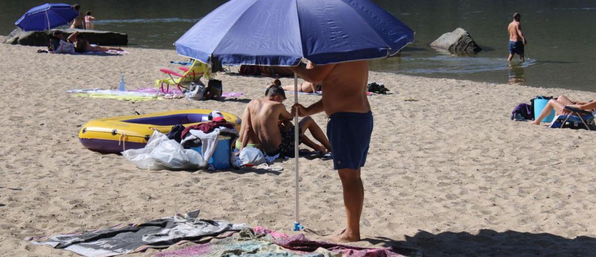Un hombre coloc una sombrilla en una playa del Lago de Sanabria. | Araceli Saavedra