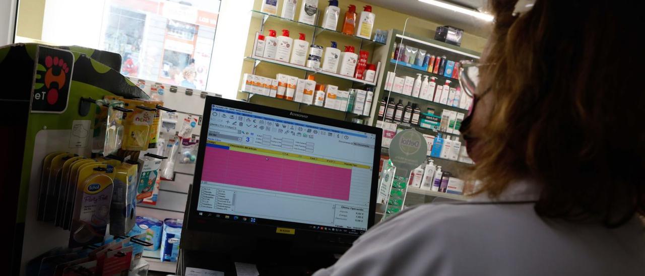 Una farmacéutica intenta acceder al sistema informático en el establecimiento De la Flor, en Avilés. | Mara Villamuza