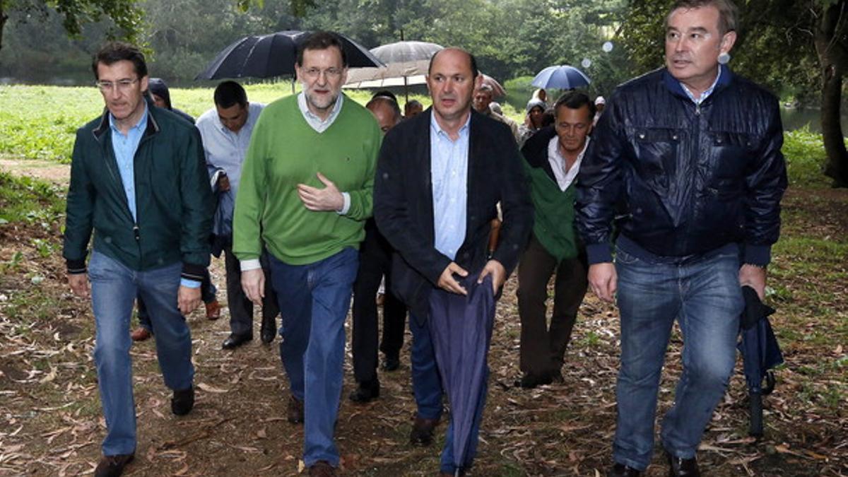 Rajoy, de verde, junto al presidente de la Xunta (izquierda) y el presidente del PP de Pontevedra, Rafael Louzán (segunda por la derecha), el sábado, durante un paso por la orilla del río Umia entre Pontearnelas y Cabanelas.