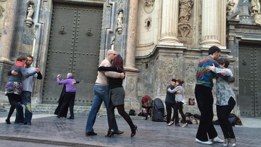 Varias parejas de aficionados al tango bailan frente a la Catedral de Murcia