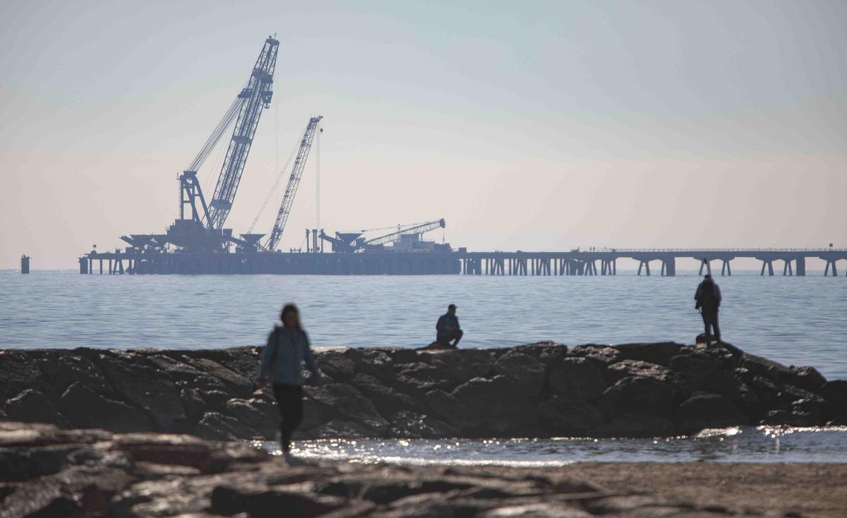 Vecinos del Port de Sagunt observan desde la playa la retirada de las tolvas del Pantalán