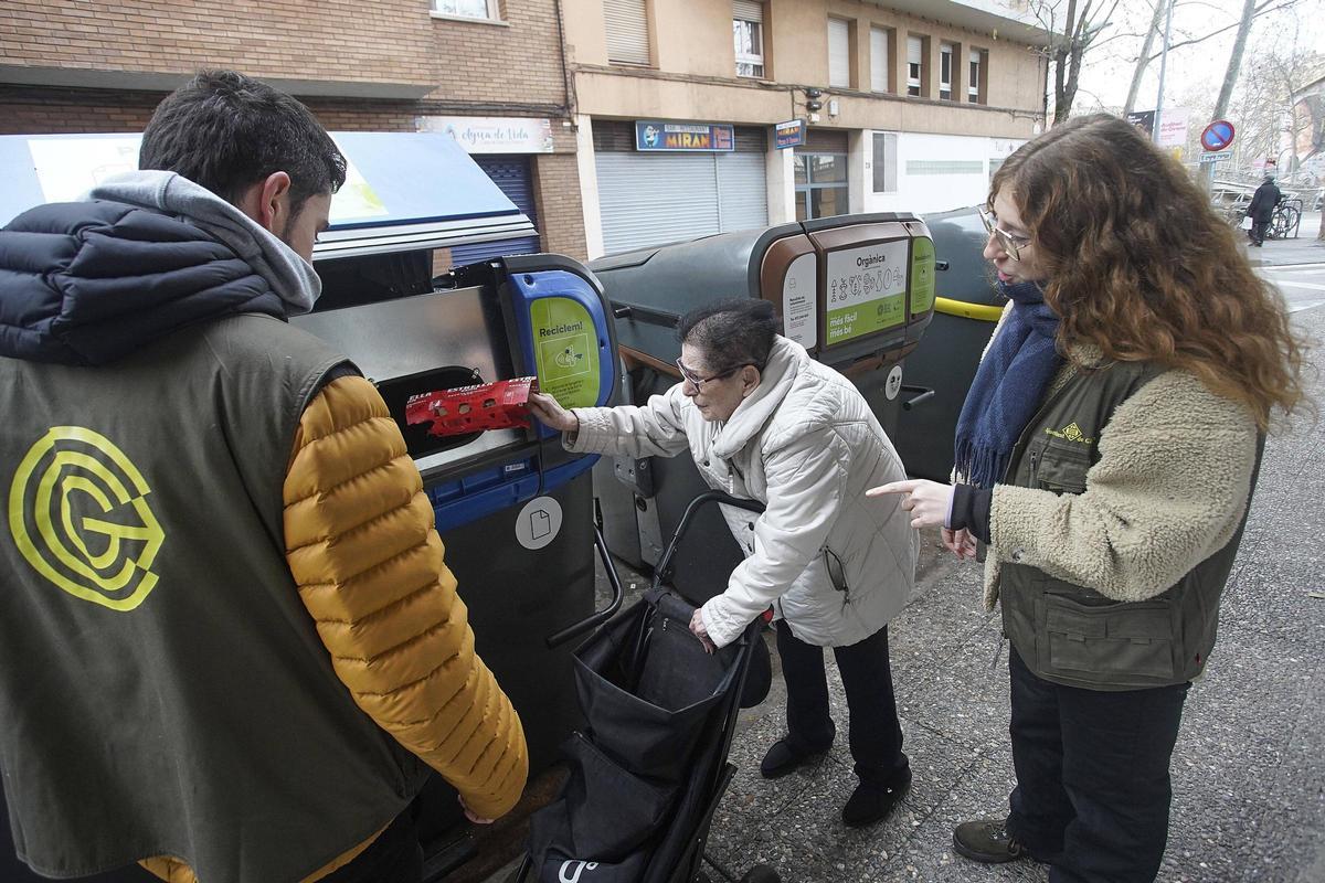 Casademont i Ganyet ajuden una veïna a utilitzar correctament el contenidor intel·ligent.