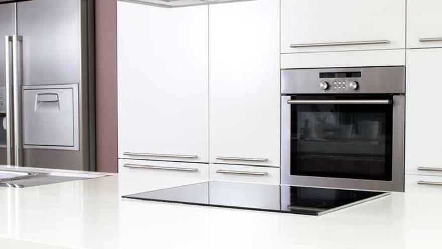 Una nevera, un horno y una vitrocerámica en una cocina reluciente.