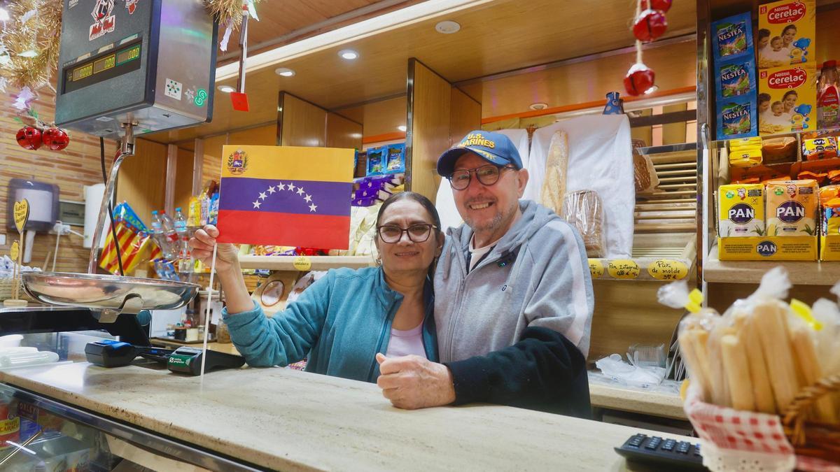 Dos venezolanos celebran la liberación de su país en su puesto en el mercado de Russafa.