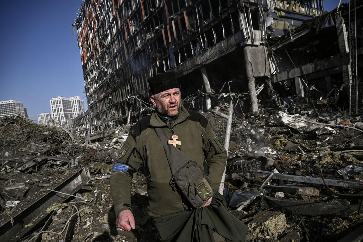 El capellán del ejército de Ucrania, Mikola Madenski, camina entre los escombros fuera del destruido centro comercial Retroville en un distrito residencial, después de un ataque ruso en la capital de Ucrania, Kiev.