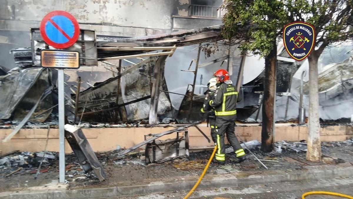 Feuerwehrleute vor dem ausgebrannten Geschäft.