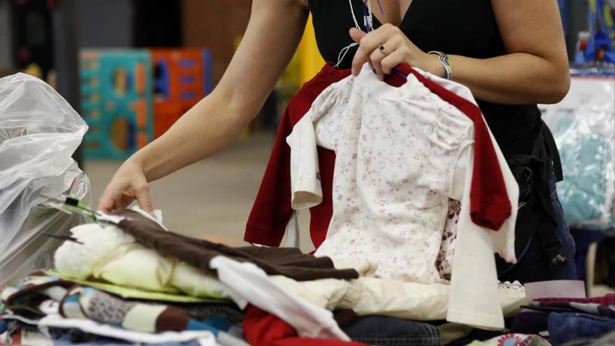 Una mujer selecciona varias prendas infantiles.