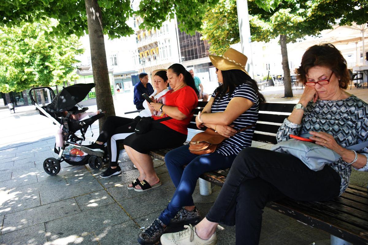 Varias personas sentadas a la sombra, este jueves, en un banco del centro de Zaragoza.